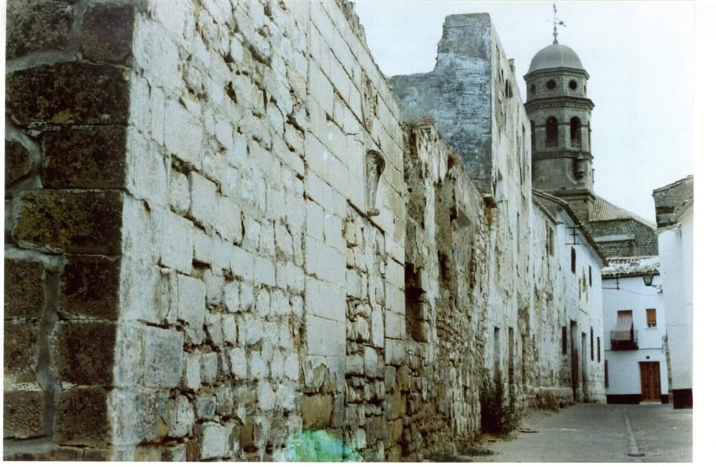 Fachada del convento antes de la rehabilitación: sillería erosionada y muro degradado, con la torre de la Antigua Universidad de Baeza al fondo.