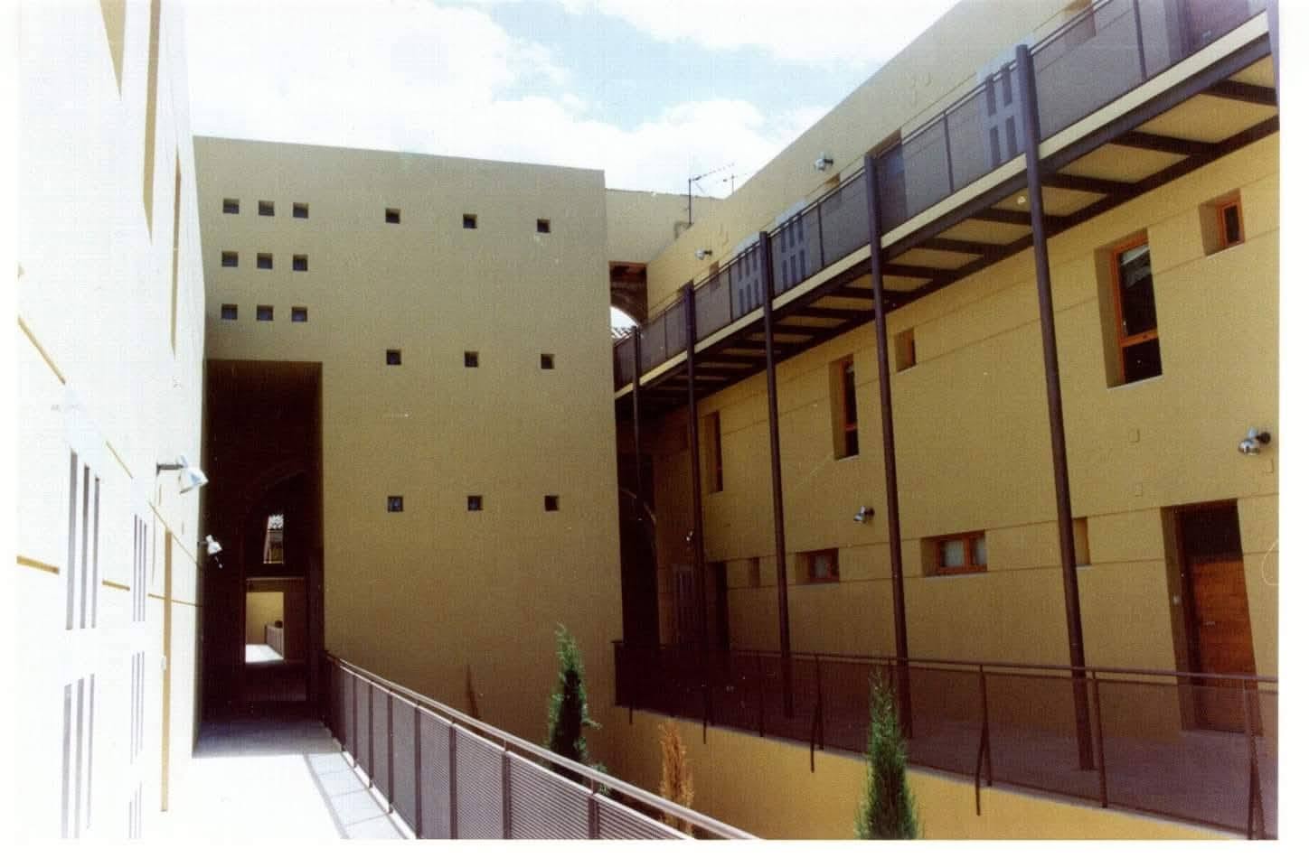 Nuevo patio interior entre las viviendas rehabilitadas: muros ocres, pasarela metálica y celosías con pequeños huecos cuadrados.